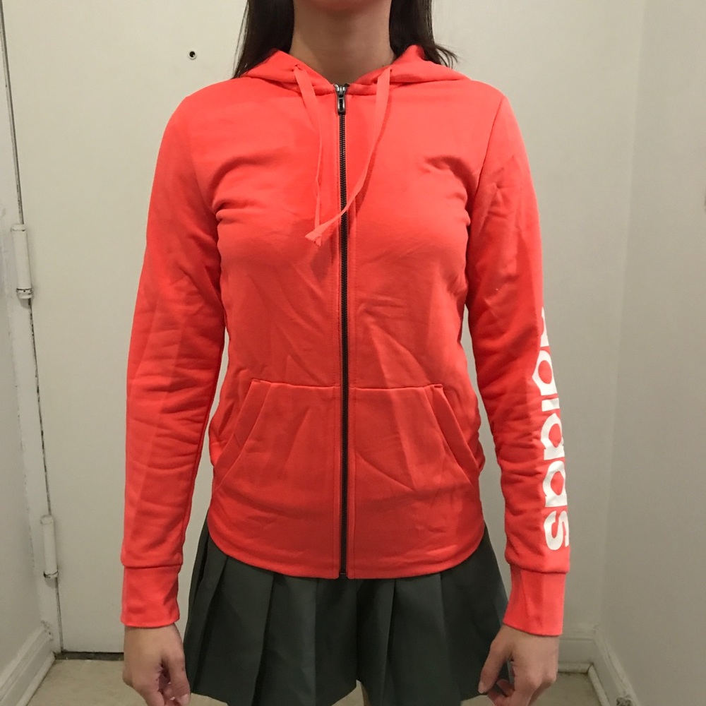 Bright pinky orange zip up Adidas hoodie.